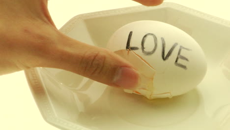 a woman's hand picks up a hardboiled egg with the word love written on it and cracks it