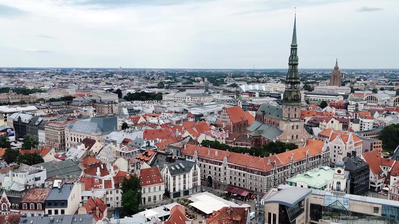 La torre della Chiesa di San Pietro domina i fitti tetti rossi e le strade storiche della Città Vecchia di Riga in un'ampia ripresa con drone.
