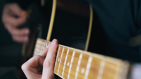 person strikes barre chords playing acoustic guitar closeup