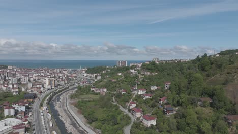 aerial view of hopa, a coastal town in artvin, turkey, showing the river, cityscape, and the black sea under a partly cloudy sky.