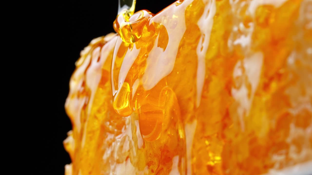 極端なマクロでハニカムの表面が現れ、自然な甘さを際立たせる濃厚な蜂蜜でコーティングされ、スローモーションで滴り落ちます。