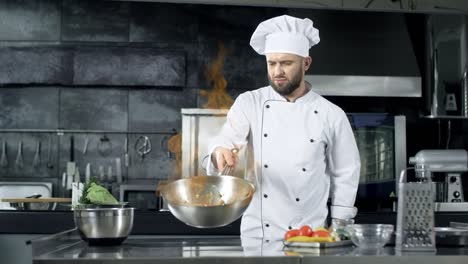 chef profesional tirando comida en una sartén con una llama ardiendo en la cocina