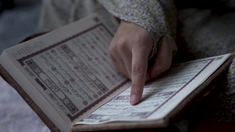 Dedicated-Muslim-woman-sits-faithfully-studying-the-Quran-Islamic-writings-CLOSE-UP