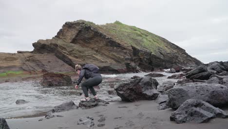 woman close to the waters edge near a rocky shore in ponta delgada, azores, portugal