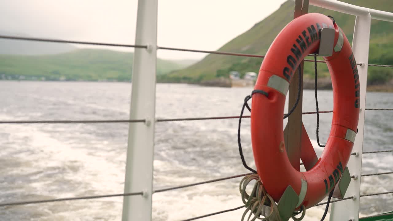 A close-up shot of a red lifebuoy on the back of a boat as it moves across a misty lake in the Connemara region of Ireland