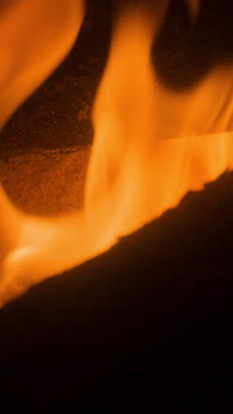 a close up of flames in log fire burning in a fireplace in vertical