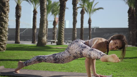 mujer estirando el cuerpo en el parque. niña practicando la pose de sage koundiya en el tapete de yoga