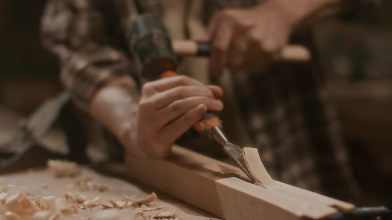 Carpenter Shaping Wood Surface with Chisel in Woodworking Workshop
