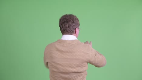 retrato de estudio de un hombre haciendo gestos de pantalla táctil vista trasera disparada contra un fondo verde