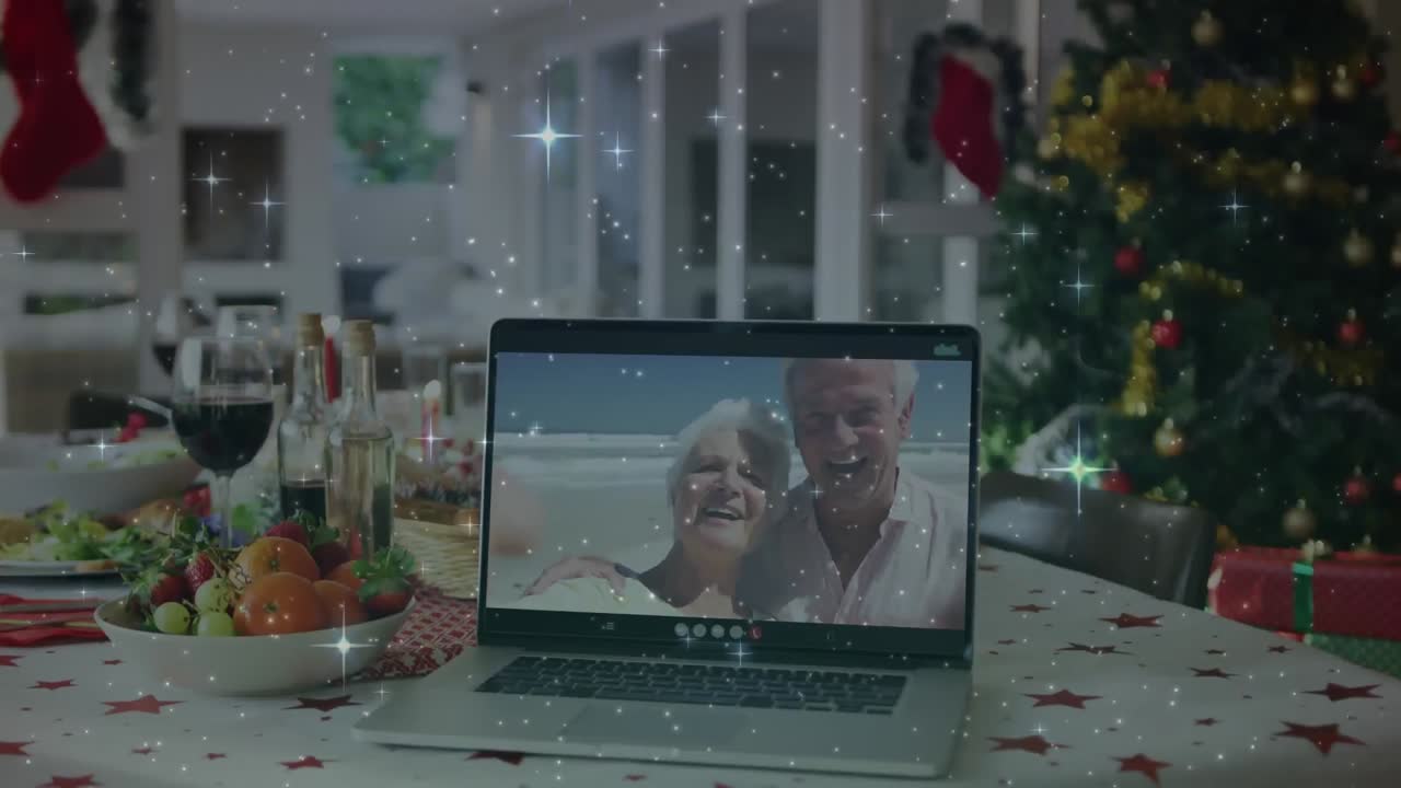 animación de estrellas sobre la mesa de navidad y una pareja mayor en la pantalla de la computadora portátil haciendo una videollamada