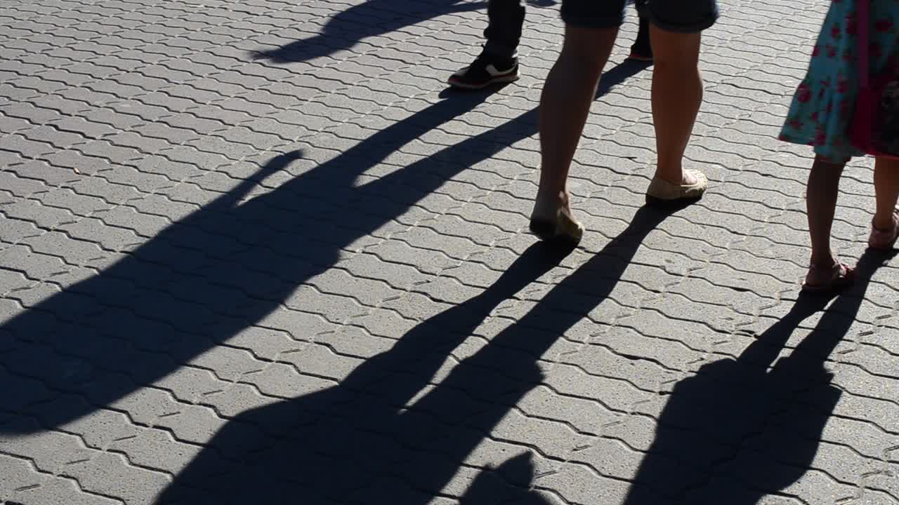 Light and shade, reflection of people in beams of the setting sun. Movement of group of people