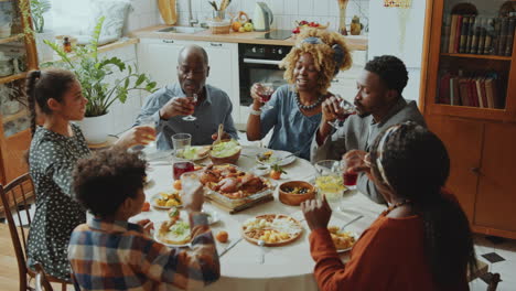 black family clinking glasses in toast and having drinks at holiday dinner