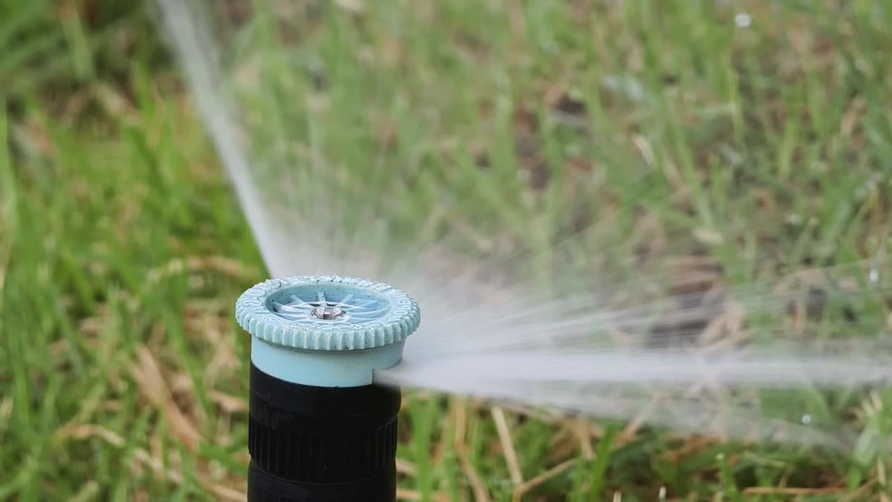 Primo piano di un irrigatore che innaffia un prato verde