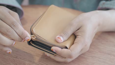 woman opening a beige leather wallet