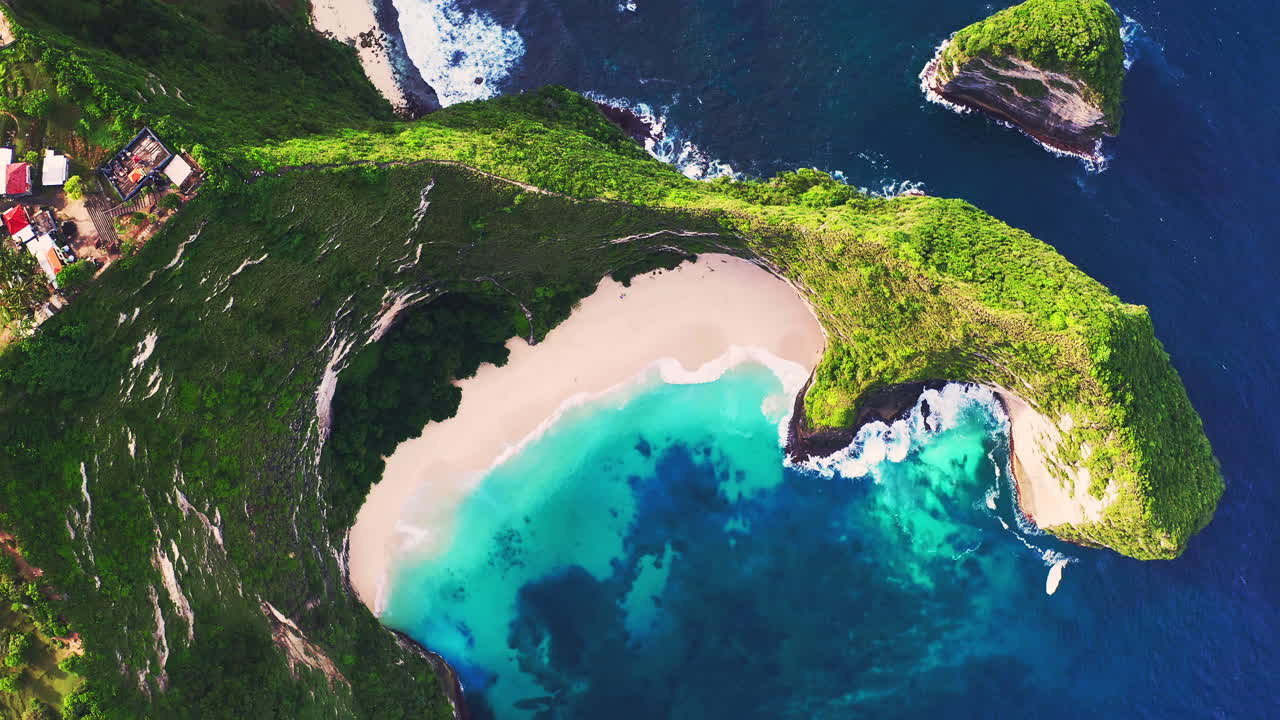 Sunlit cape ridge with green foliage around tropical blue lagoon beach