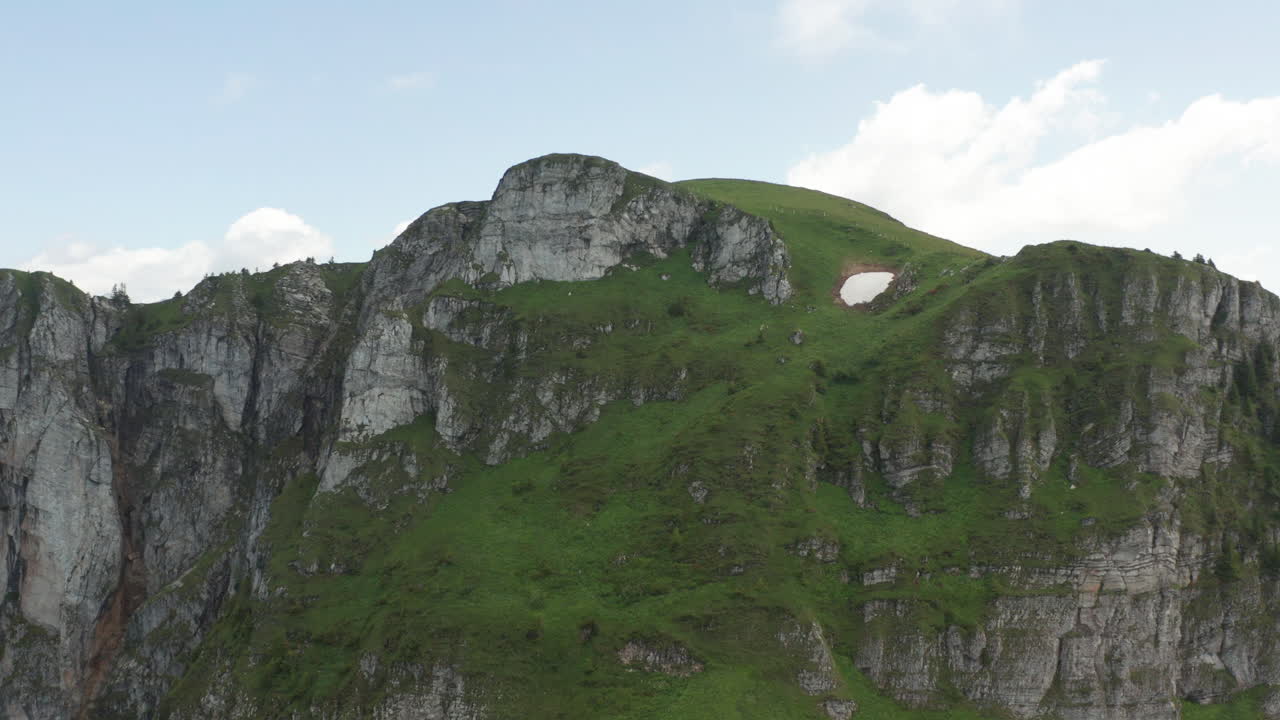 Volando verso e sopra una bellissima formazione rocciosa in Svizzera, rivelando una splendida valle verde intenso