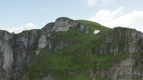 flying towards and over beautiful rock formation in switzerland, revealing a stunning deep green valley