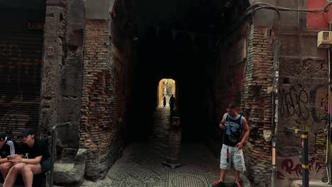 people in alleyway with graffiti in naples