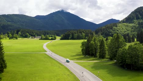 Grüner-Wohnmobil,-Der-Auf-Einer-Leeren-Straße-In-Einer-Wunderschönen-Berglandschaft-Fährt