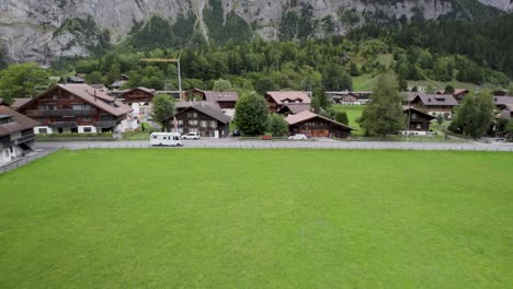 A-camper-passes-through-a-picturesque-Swiss-village-surrounded-by-lush-greenery