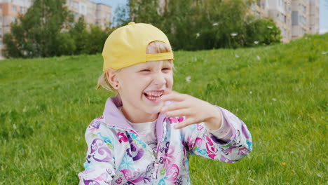 blonde girl in a yellow cap playing with dandelions 1