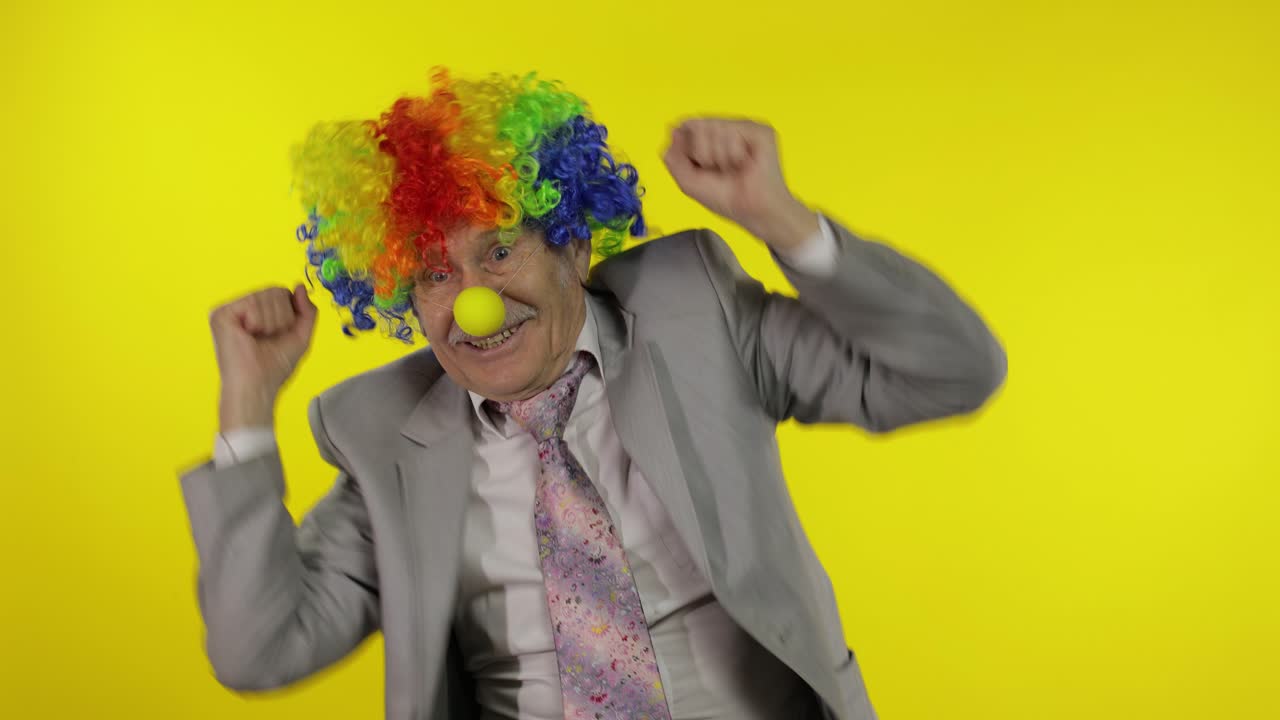 el viejo payaso hombre de negocios bailando, celebrando. el dinero, el dólar, el dinero cae de arriba.