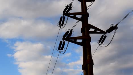 Low-angle-view-of-high-tension-power-lines-against-clouds-at-dusk