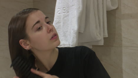 woman brushing her hair in a hotel bathroom