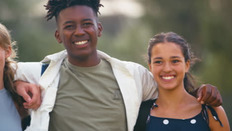 close up portrait of smiling multi-cultural high school or secondary pupils sitting on wall outdoors