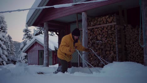 man scraping thick snow using sleigh shovel on countryside village