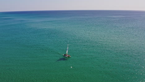 beautiful aerial view of a catamaran sailing on sparkling blue tropical water