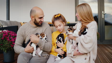 A-happy-family-with-a-child-and-a-pet-sits-on-the-veranda-of-the-sleet-house.-4k-video