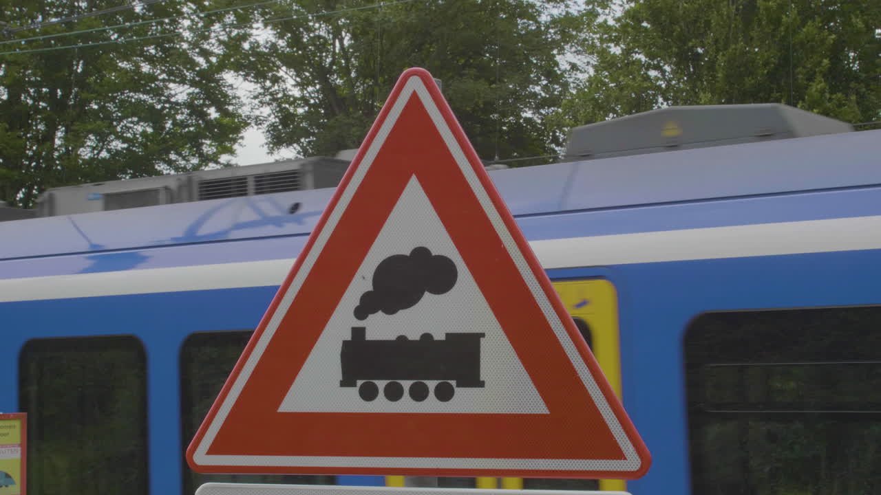 무방비 수준 건널목 근처의 무방비 수준 건널목 경고 표지판 뒤에 지나가는 기차