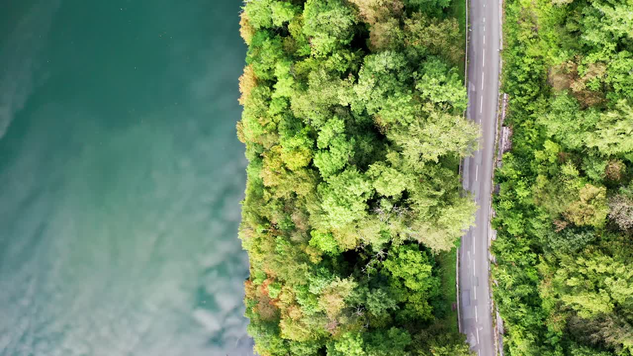 nubes reflejadas en el profundo agua verde-azul del río a través del bosque con una pequeña carretera, dron aéreo