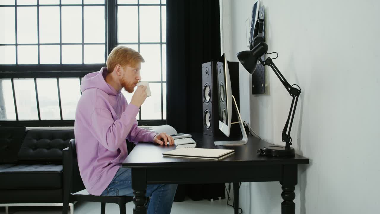 un hombre trabajando en un escritorio, bebiendo café.