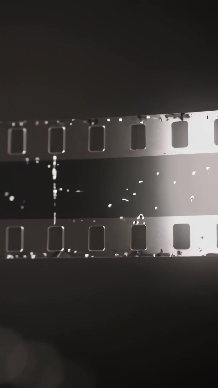 Verticale video: Bewegend licht toont stof en krassen op 35mm film in een lichtbak met perforaties.