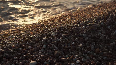 close up shot of the small stones that are near sea, sun is falling on the water