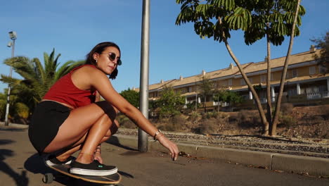 capturado en cámara lenta, una mujer joven disfruta de un paseo en longboard cerca de las palmeras, vistiendo pantalones cortos y zapatillas de deporte en el entorno de verano