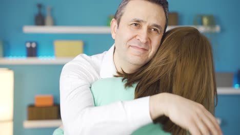 un padre feliz y atento abrazando a su joven hija adulta.
