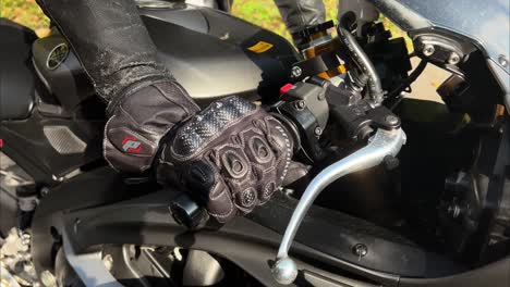 close up shot of male hand in gloves twisting the throttle grip and revving the engine of a motorcycle