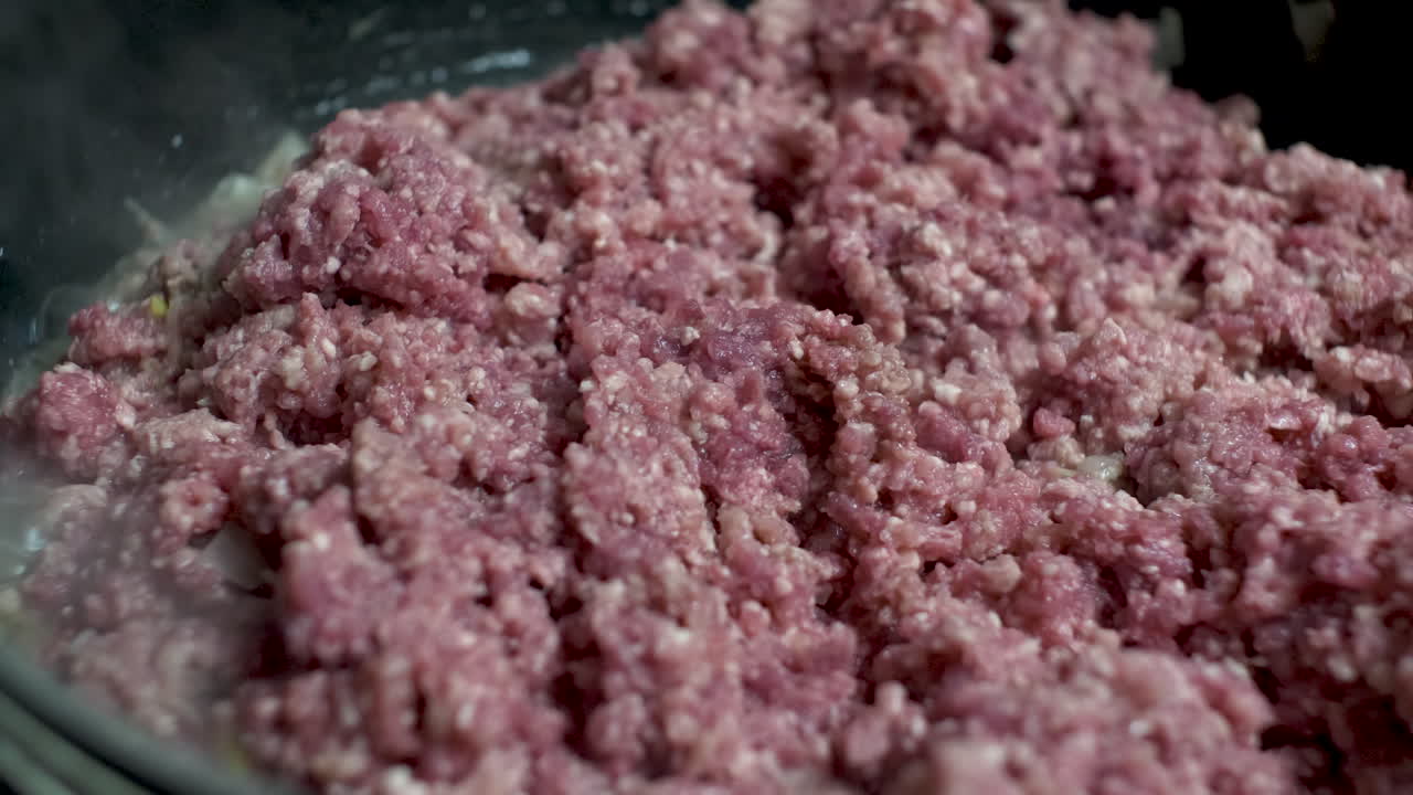 disparo de cerca de carne de res picada cruda siendo colocada en una sartén caliente