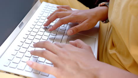las manos de una adolescente biracial usando el teclado de la computadora portátil, en cámara lenta