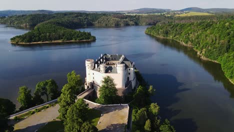 orlík castle perched on a forested peninsula surrounded by vitava river waters