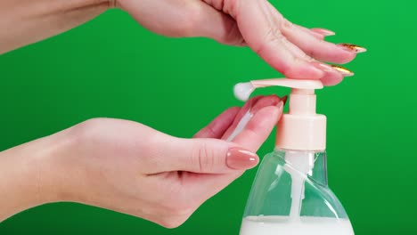 female hands pushing dispenser and using liquid soap on green background. prevention of viruses, safety protection. antibacterial foaming sanitizer close-up