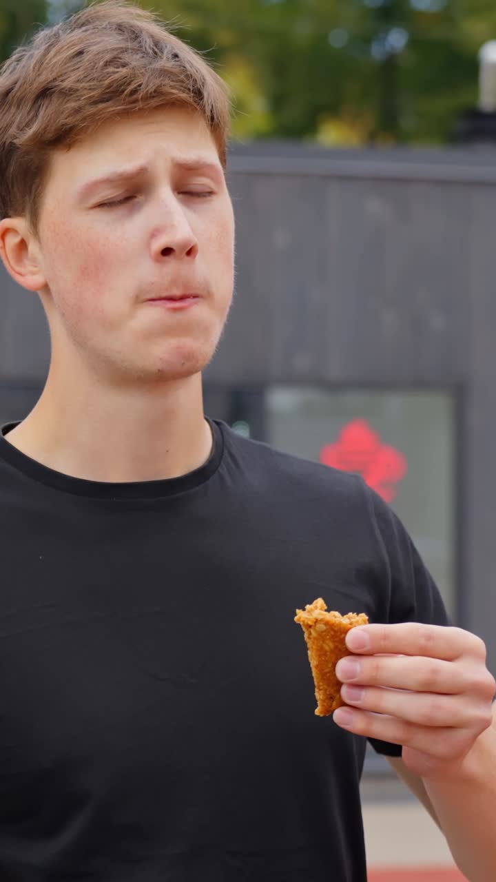 Young man enjoying energy bar outdoors on a sunny day, relaxed lifestyle, vertical