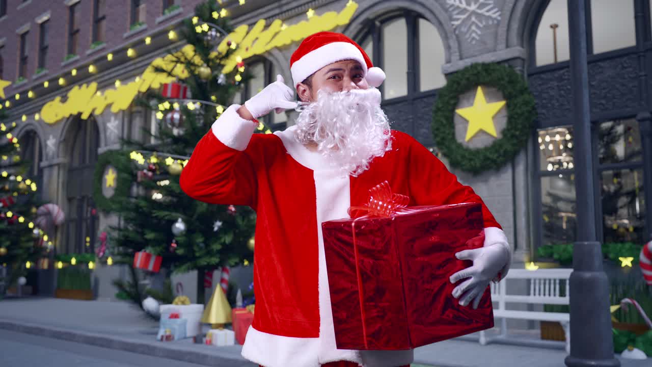 papá noel asiático sosteniendo un regalo y haciendo un gesto telefónico mientras está de pie en la noche de navidad