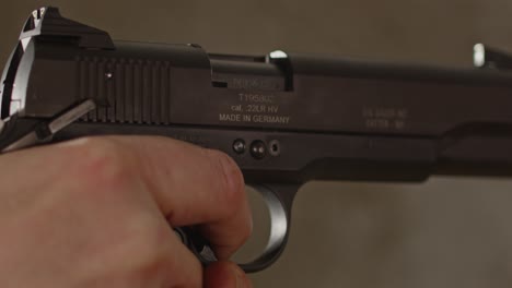 extreme close up of pistol being aimed with a man's finger on the trigger