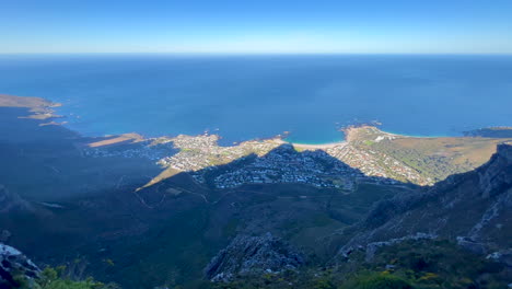 Sunrise-morning-hike-exploring-top-of-Table-Mountain-Cape-Town-South-Africa-pan-right-scenic-view-of-mountain-cliffside-lush-spring-summer-grass-flowers-deep-blue-ocean-incredible