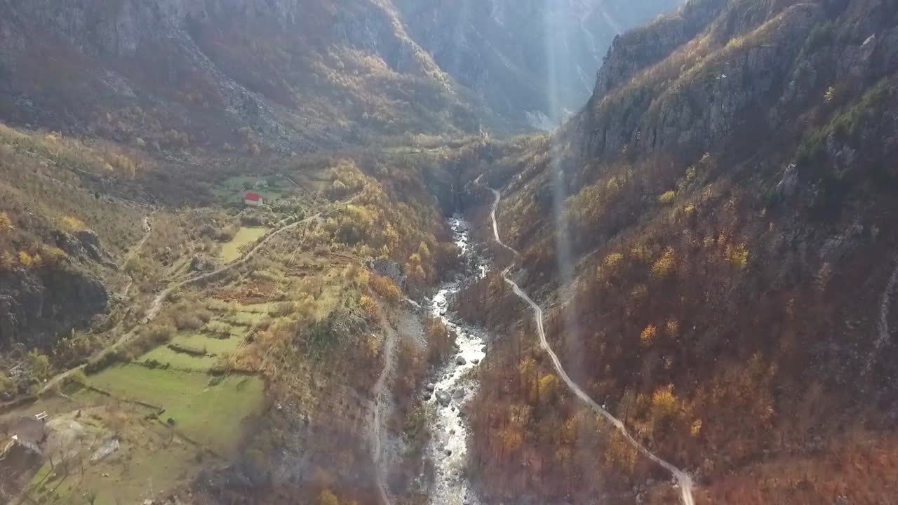 hermoso valle de montaña al amanecer durante la temporada de otoño con el sol atravesando y el río fluyendo a través de los alpes en albania