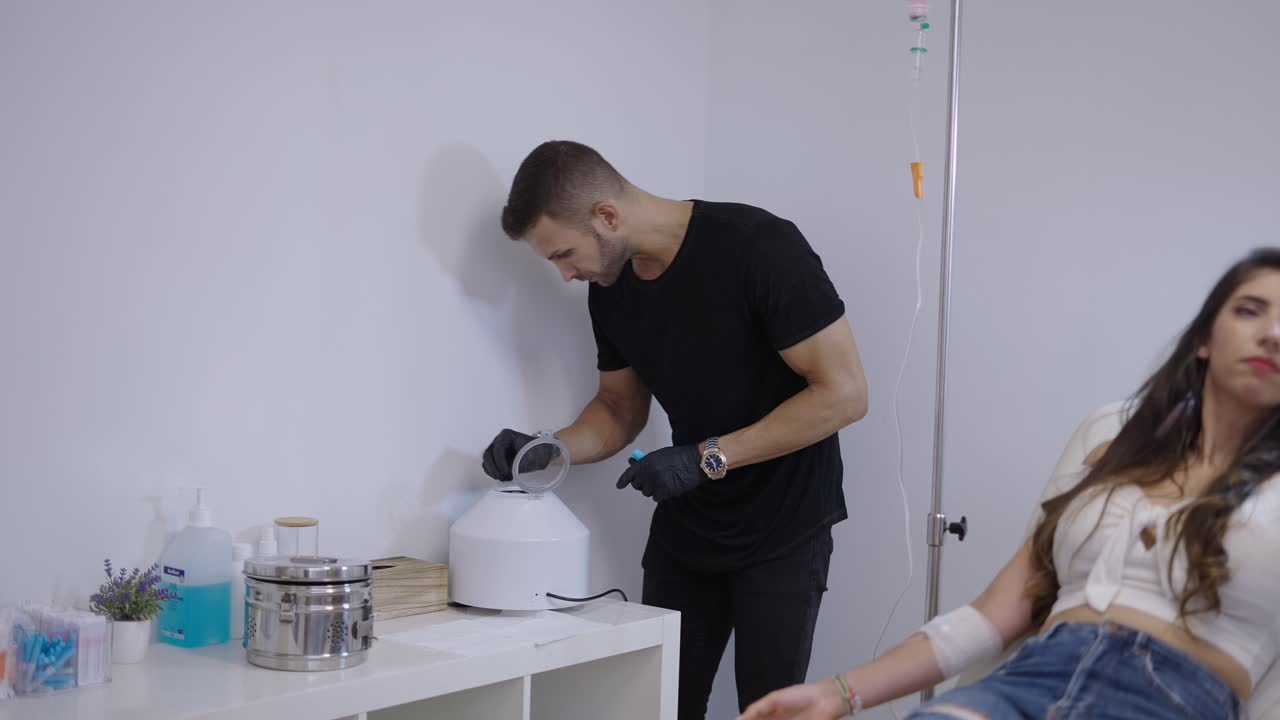 Medical professional operating a centrifuge while a patient receives an IV drip